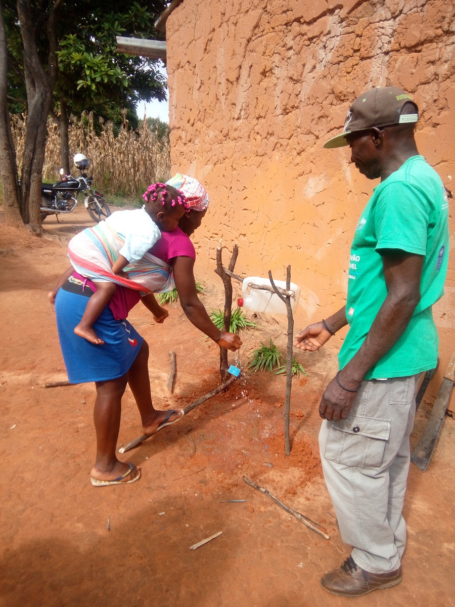 Membro de grupos de acção ambiental e suas famílias começando a usar seu Tippy Tap no bairro da Maiaia